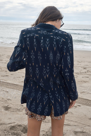 Woman at the beach wearing an ikat double breasted jacket with coordinating tapestry sun short, back view.