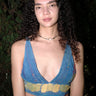 A woman wearing a blue handmade bra with rainbow threads and a necklace.