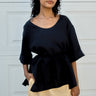 Woman wearing a black top and yellow skirt against a white wall