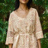 Woman wearing a patterned top with a belt in a natural setting