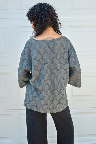 Person wearing a textured gray lace tee with a white background