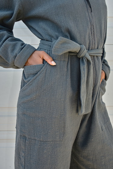 Gray jumpsuit  with a belt around the waist on a neutral background
