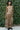 Woman wearing a floral dress standing outdoors with greenery in the background