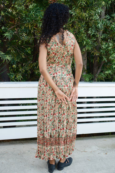 Woman wearing a floral dress standing outdoors with greenery in the background