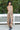 woman wearing a floral pleated dress in front of greenery 