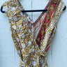 Floral dress with a red and green pattern on a hanger against a white wooden background