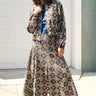 A woman standing in front of a garage door, wearing a midi-length skirt in a geometric tapestry, denim tee top and matching tapestry jacket.
Worn with espadrilles
