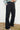 Person wearing black pants against a white wall.