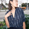 A woman wearing a black Ikat shrug  paired with a silver necklace and earrings.