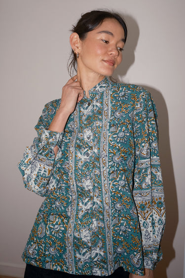 Woman wearing a patterned blouse against a plain background