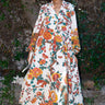 Woman wearing a floral caftan standing outdoors with greenery around