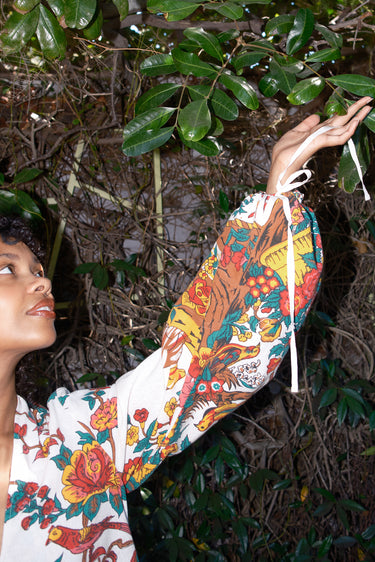 Person wearing a colorful floral caftan with sleeves in a natural setting