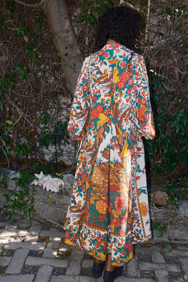 Person wearing a colorful floral dress standing in a garden.