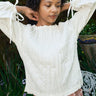 Woman wearing a white blouse with ruffled sleeves in an outdoor setting