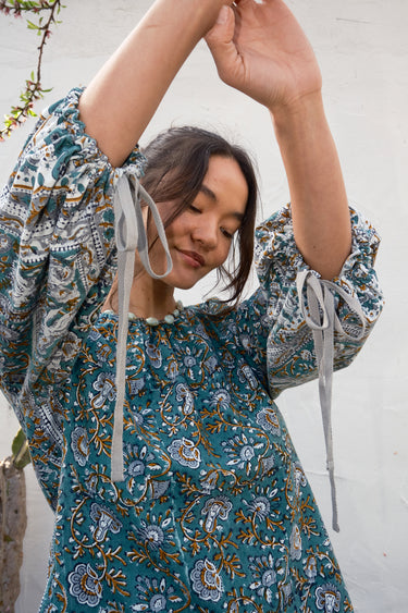 Woman wearing a blue patterned blouse with a white background