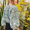 Woman wearing a floral blouse standing among yellow flowers