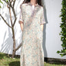 A woman standing outdoors wearing a floral print maxi dress with a shirt collar and sleeves, featuring a handloom Indian Tapestry fabric.