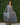 Person wearing a long gray  skirt and shirt  against a green leafy background