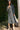 Woman in a pewter dress standing outdoors next to a palm tree