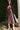 Woman in a black fig dress with a black cardigan standing outdoors next to a palm tree.