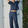 A person wearing a navy blue flare legged full length pant with a mid rise and hand woven, hand block printed Indian Tapestry.