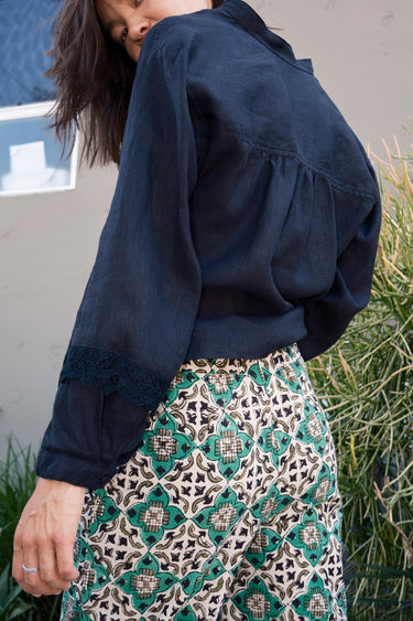 A person wearing a flare legged full length pant with a mid rise and a hand block printed Indian Tapestry design.
back view detail 