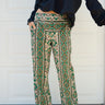 A person wearing a flare legged full length pant with a mid rise and a hand block printed Indian Tapestry design.