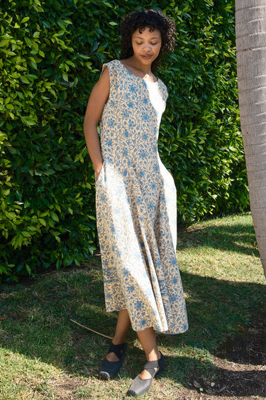 Woman wearing a floral dress standing outdoors with greenery in the background