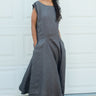 Woman wearing a gray dress standing in front of a white wall.