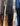 A close-up view of multiple garments hanging on a rack, including black long-sleeve tops and patterned dresses or kaftans in cream, blue, and multicolor floral prints.