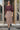 Woman wearing a black fig top and floral skirt standing in front of a glass door.