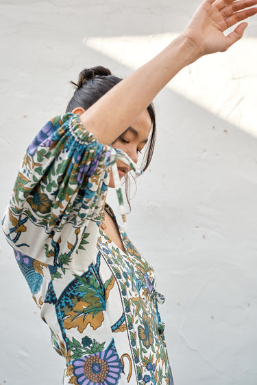 A woman modeling a maxi dress with a tree of life print, featuring voluminous 3/4 sleeves and a V-neckline.
