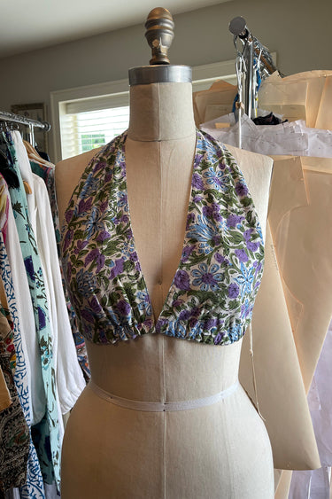 A floral printed bikini top with ties around the neck and back, displayed on dress form.