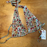 A halter style bikini top with a floral pattern in red and green on an ecru background, displayed on a flat surface.
