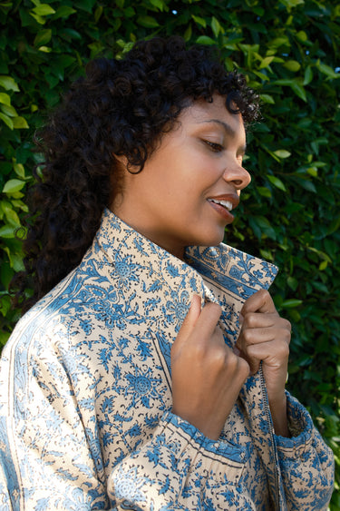 Woman wearing a patterned jacket against a green leafy background