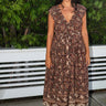 A woman wearing a raisin floral tapestry wrap dress with elastic neckline and pockets, standing outdoors.