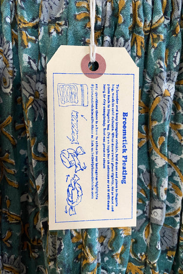 Close up of a hang tag showing the care instructions for the broomstick pleat.