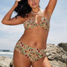 A woman at the beach wearing a beige ground, red and brown floral tapestry bandeau bikini top and matching bikini bottom.