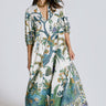 A model standing in a white photo studio wearing a maxi caftan, with three quarter balloon sleeves and  pockets. The caftan is cut from a blue and green hand block printed tree of life tapestry