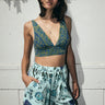 A woman standing outside wearing an aqua ground floral tapestry short with dark blue paisley print bra top. 