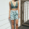 A woman standing outside wearing a dark blue paisley tapestry bra top with aqua ground floral tapestry short 