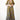 A woman standing in a studio with white walls wearing a maxi caftan cut in an olive green tree of life handloom tapestry.