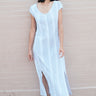 a woman standing by a pink wall wearing a long sheath dress cut for white gauze with a black pencil stripe. 